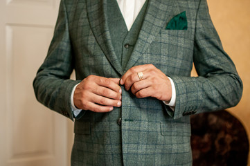 groom buckles the button on his jacket