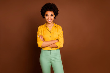 Photo of stunning business dark skin curly lady looking colleagues good mood arms crossed friendly smiling wear yellow shirt green pants isolated brown color background