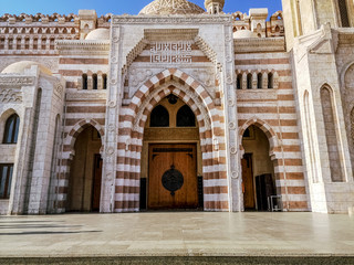Fototapeta na wymiar Egypt, Sharm El Sheikh - January 18, 2020: Entrance to the Al Mustafa Mosque in Sharm El Sheikh, front view. Facade of a striped Muslim temple in an Egyptian tourist city, close-up
