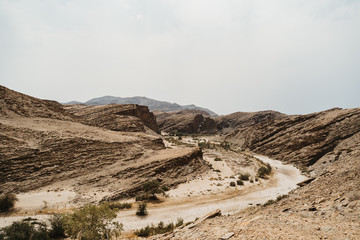 road through dry river in moon landscape with rocks, stones and mountains