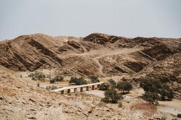 Fototapeta na wymiar road through dry river in moon landscape with rocks, stones and mountains