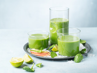 Green smoothie in glass with organic ingredients, vegetables on a light background with copy space. Selective focus. Food and drink, healthy dieting, nutrition, alkaline, vegan, vegetarian concept.