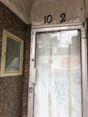 verlassenes Haus mit Haustür aus Glas und Hausnummer 102 