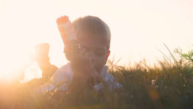 boy shoots from toy weapons gun. little boy plays war lies on the ground shoots an automatic blaster weapon of the future. slow motion sunset silhouette lifestyle children and weapons war concept