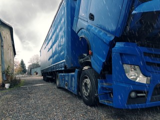 A broken truck, with the cab lowered, is waiting for a repair car service.It`s rainy.Broken truck, mobile car service, road and rain. Traffic complications.