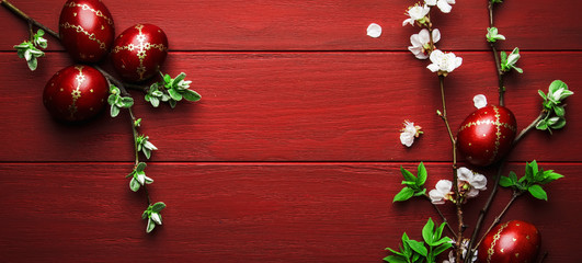 Easter eggs and spring white flowers on Easter red wood background with copy space