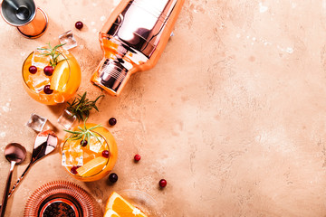 Orange Cranberry Rosemary and Vodka cocktail, copper bar tools, beige background, hard light, top...