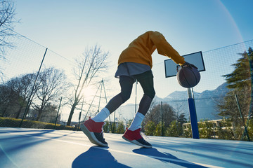 Athletic black man showing his backetball skills on court outdoors.