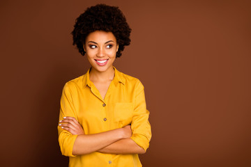 Obraz na płótnie Canvas Photo of beautiful funny business dark skin curly lady beaming smiling arms crossed good mood look interested empty space wear yellow shirt isolated brown color background
