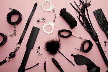 top view of black sex toys on pink background - obrazy, fototapety, plakaty