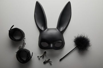 Fototapeta top view of black rabbit mask and sex toys on white background obraz