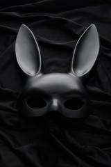 top view of rabbit mask on black textile background