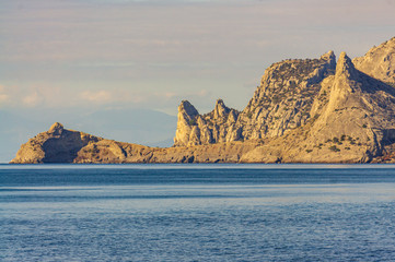 Panorama of Galitsyn trail in New World from Cape Alchak. Trail is laid along steep cliffs. High peaked cliffs emerge from deep sea. Velvet season. Sudak, Crimea, Russia. October, 2019.