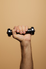 Fototapeta na wymiar cropped view of man holding dumbbell isolated on beige