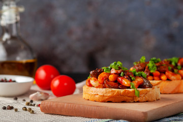 Bruschetta with beans and mushrooms on a wooden board
