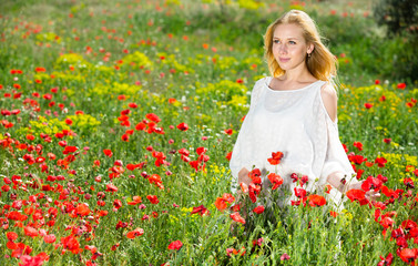 Naklejka na ściany i meble Woman wearing white dress in poppy field and enjoying summer day