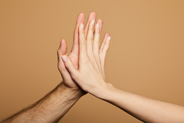 cropped view of man and woman giving high five isolated on beige