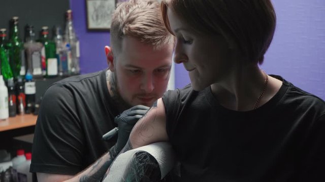 Young tattooer getting tattoo of snake in salon, process