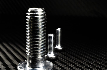 unterschiedliche schrauben die glänzen auf einem untergrund aus carbon