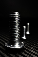 schrauben in verschiedenen größen auf untergrund aus carbon glänzend