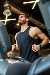 Fototapeta na wymiar Young man running on treadmill at gym