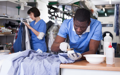 Man dry cleaning clothes in laundry