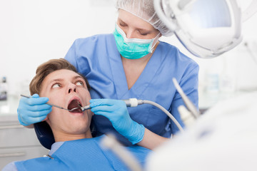 Male patient sitting on chair in dental office getting dentist treatment