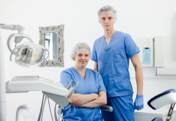 Obraz premium Two professional confident dentists posing near dental chair in clinic