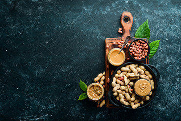 Peanut butter and nuts on a black stone background. Healthy food. Top view.