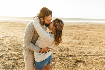 Beautiful young couple standing at the sunny beach