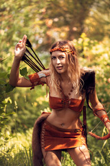 Beautiful girl archer with long blond hair with a bow and arrows dressed in leather
