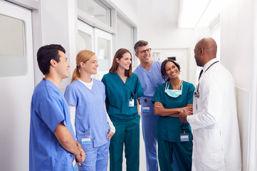 Multi-Cultural Medical Team Having Meeting In Hospital Corridor - Powered by Adobe