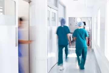 Fotobehang Motion Blur Shot Of Medical Staff Wearing Scrubs In Busy Hospital Corridor © Monkey Business