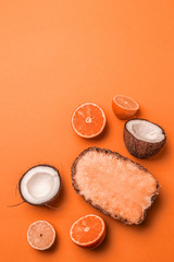 Assorted exotic fruits on an orange background. Pineapple, coconut, orange and lemon half in flat lay style