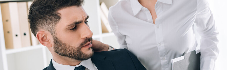 Obraz premium panoramic shot of secretary with big breast touching shocked businessman in office