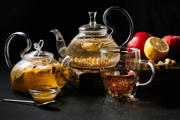 Glass teapots with fruit tea in composition on black background