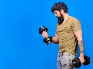 Bearded man raising dumbbells. Muscular fitness man working out with dumbbells. Sportsman making weightlifting. Man with dumbbells during an exercise. Strong handsome sportsman making weightlifting.