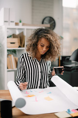 Beautiful african businesswoman in office. Woman at work drinking coffee while working. 