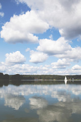 clouds over the lake and reflecting in the water. sailboat at the horizon 