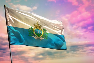 Fluttering San Marino flag on colorful cloudy sky background. Prosperity concept. - obrazy, fototapety, plakaty