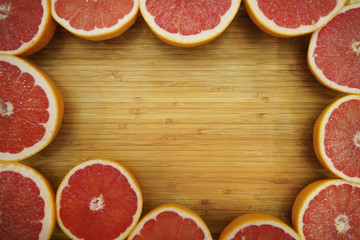 Fototapeta na wymiar Grapefruit frame on the bamboo wood board. Fresh jusy fruits