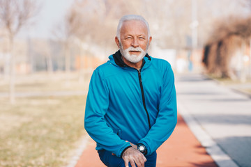 A senior man stretching legs in the park.