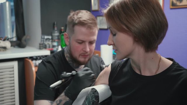 Video of man doing black tattoo of snake in studio