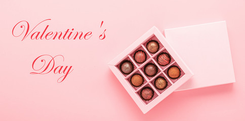 Box of chocolates and text Valentine's Day on a pink background. Concept of holiday and love. Horizontal frame