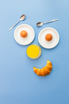 Fun breakfast concept with abstract smiling, happy human face made of breakfast items on blue background.