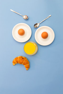 Fun breakfast concept with abstract angry, grumpy human face made of breakfast items on blue background.