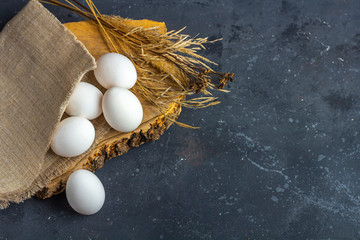 Easter flat lay rustic composition of fresh white eggs in egg cell  on dark background. Zero waste, eco friendly and natural material. Farming and healthy eating concept.