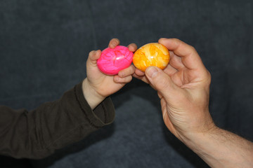 hands of an adult and a child with colored colored eggs, easter concept