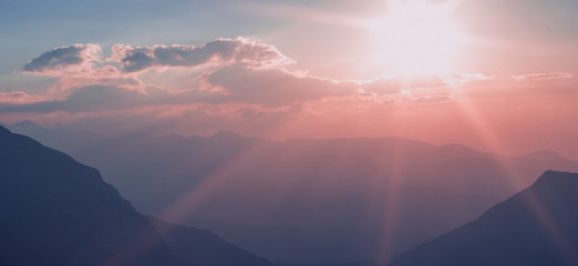 unfocused idyllic sun set rays of light above mountain silhouettes picturesque landscape wallpaper background pattern space for copy or your text here purple and phantom blue colors