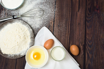 Maslenitsa is a traditional holiday in February . Ingredients for baking pancakes. frying pan, eggs, flour, egg beater, on a dark wooden background top view. top view, place to copy text, recipe.